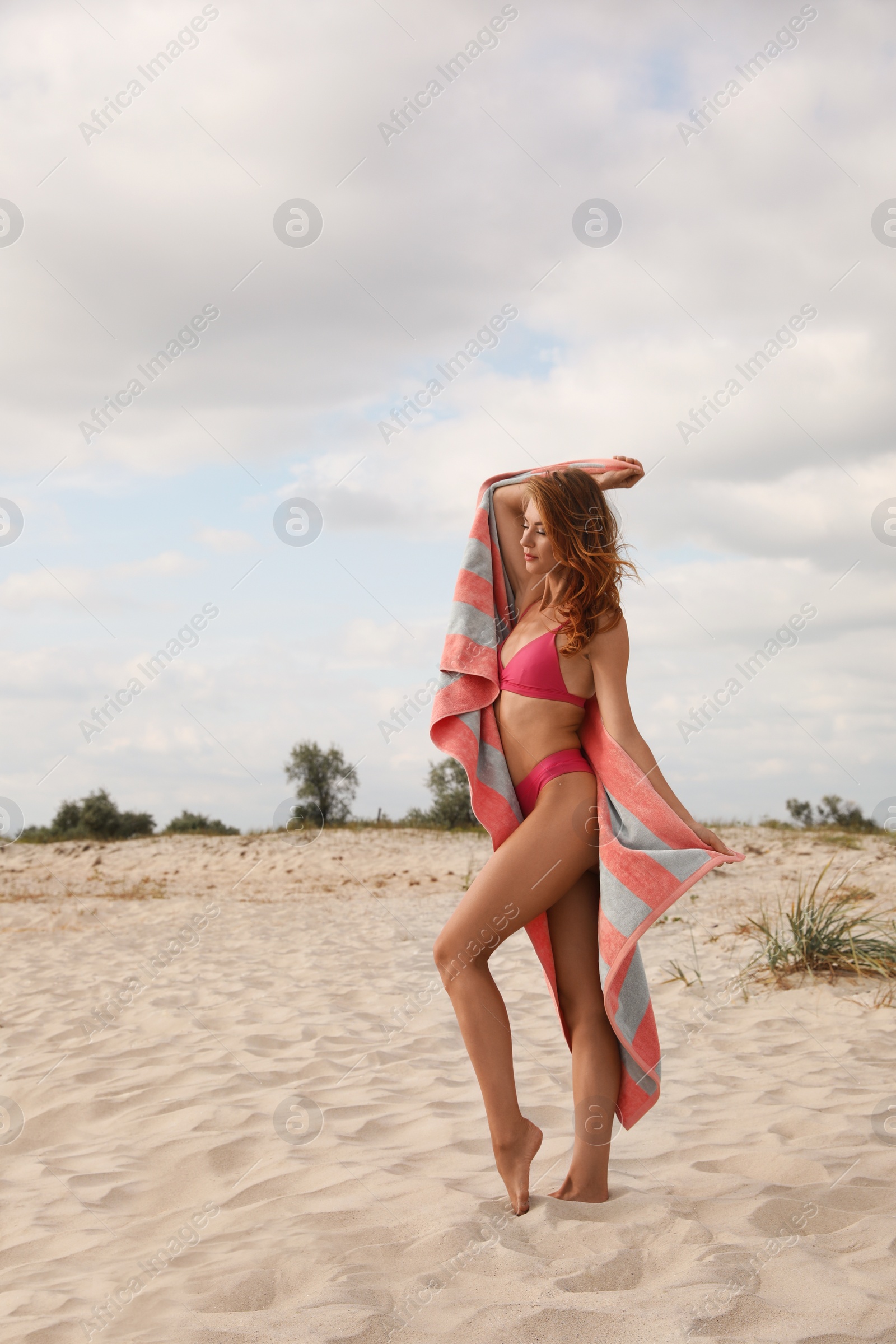 Photo of Beautiful woman in bikini with beach towel on sand