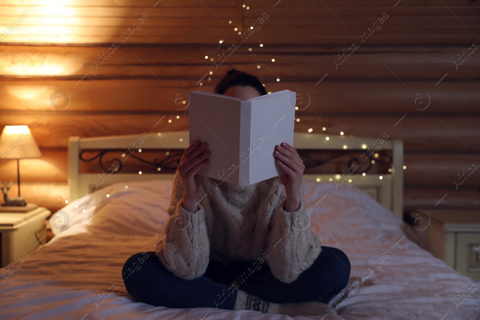 Photo of Young woman reading book on bed at home