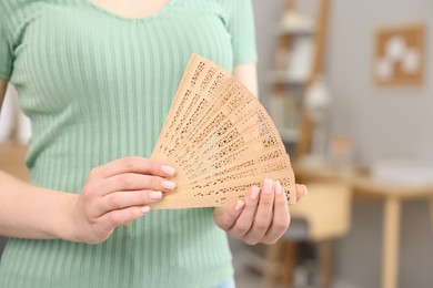 Photo of Woman with hand fan at home, closeup. Space for text