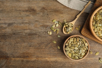 Photo of Flat lay composition with raw pumpkin seeds on wooden table, space for text