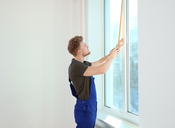 Service man measuring window for installation indoors. Space for text