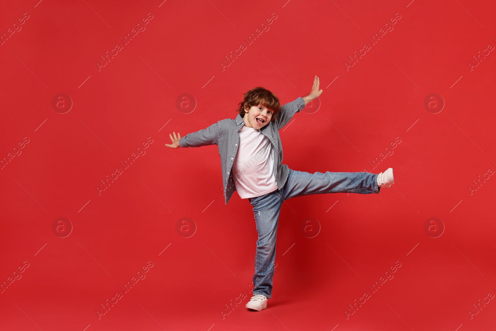 Photo of Happy little boy dancing on red background. Space for text