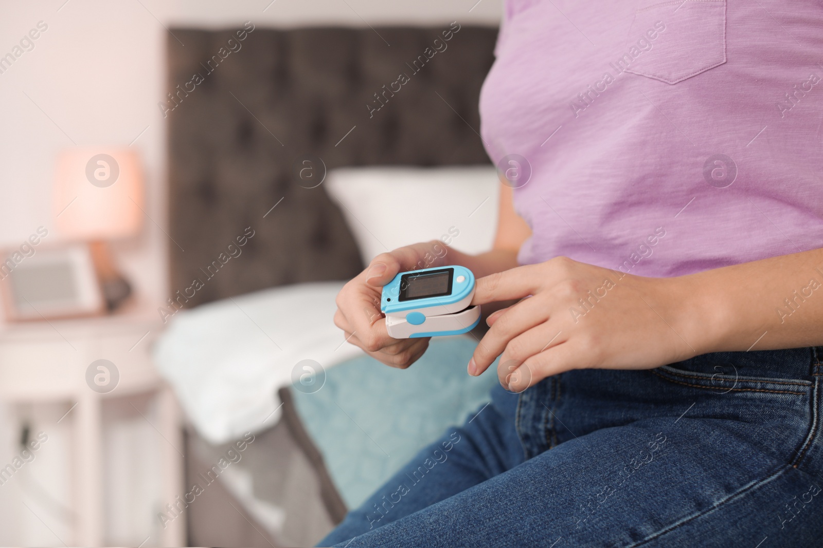 Photo of Young woman checking pulse with digital medical device indoors, closeup. Space for text