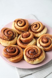 Many tasty cinnamon rolls on white table