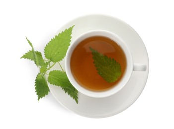 Photo of Cup of aromatic nettle tea and green leaves on white background, top view