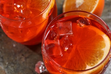Aperol spritz cocktail, ice cubes and orange slices in glasses on table, closeup