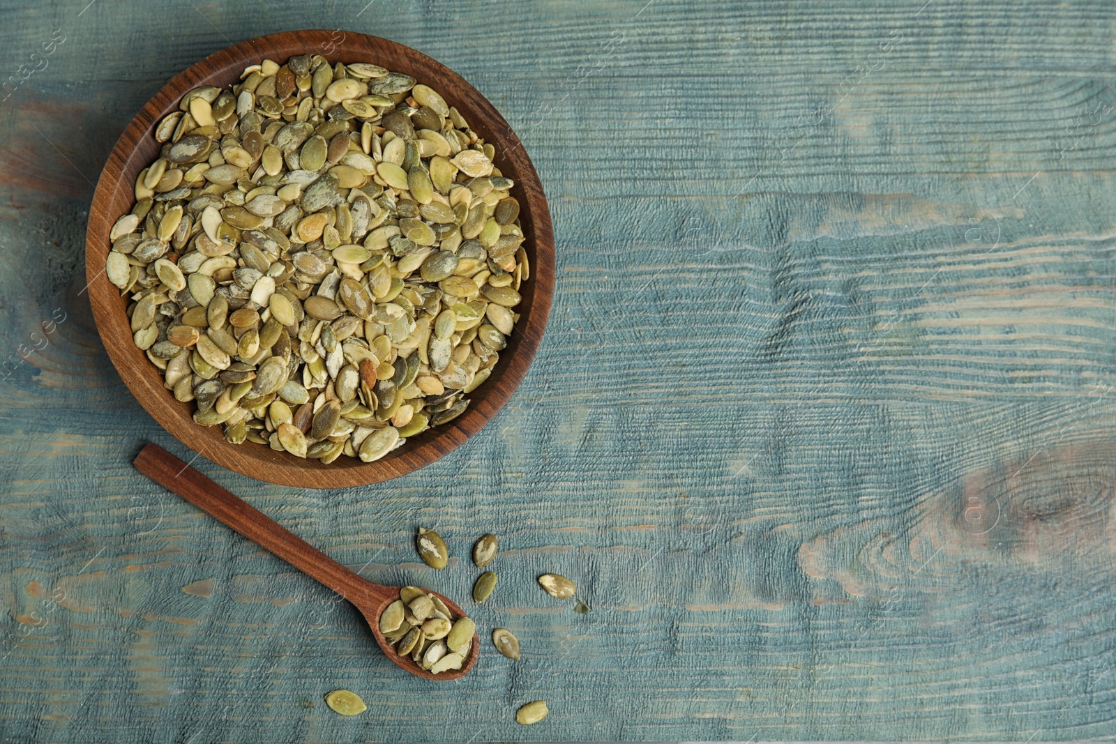 Photo of Raw pumpkin seeds on blue wooden table, flat lay. Space for text