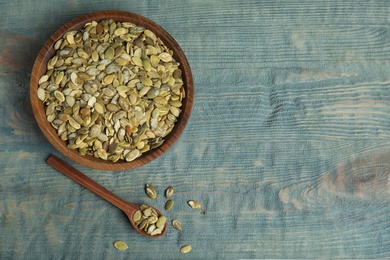 Photo of Raw pumpkin seeds on blue wooden table, flat lay. Space for text