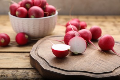 Photo of Board with fresh ripe radishes on wooden table, closeup