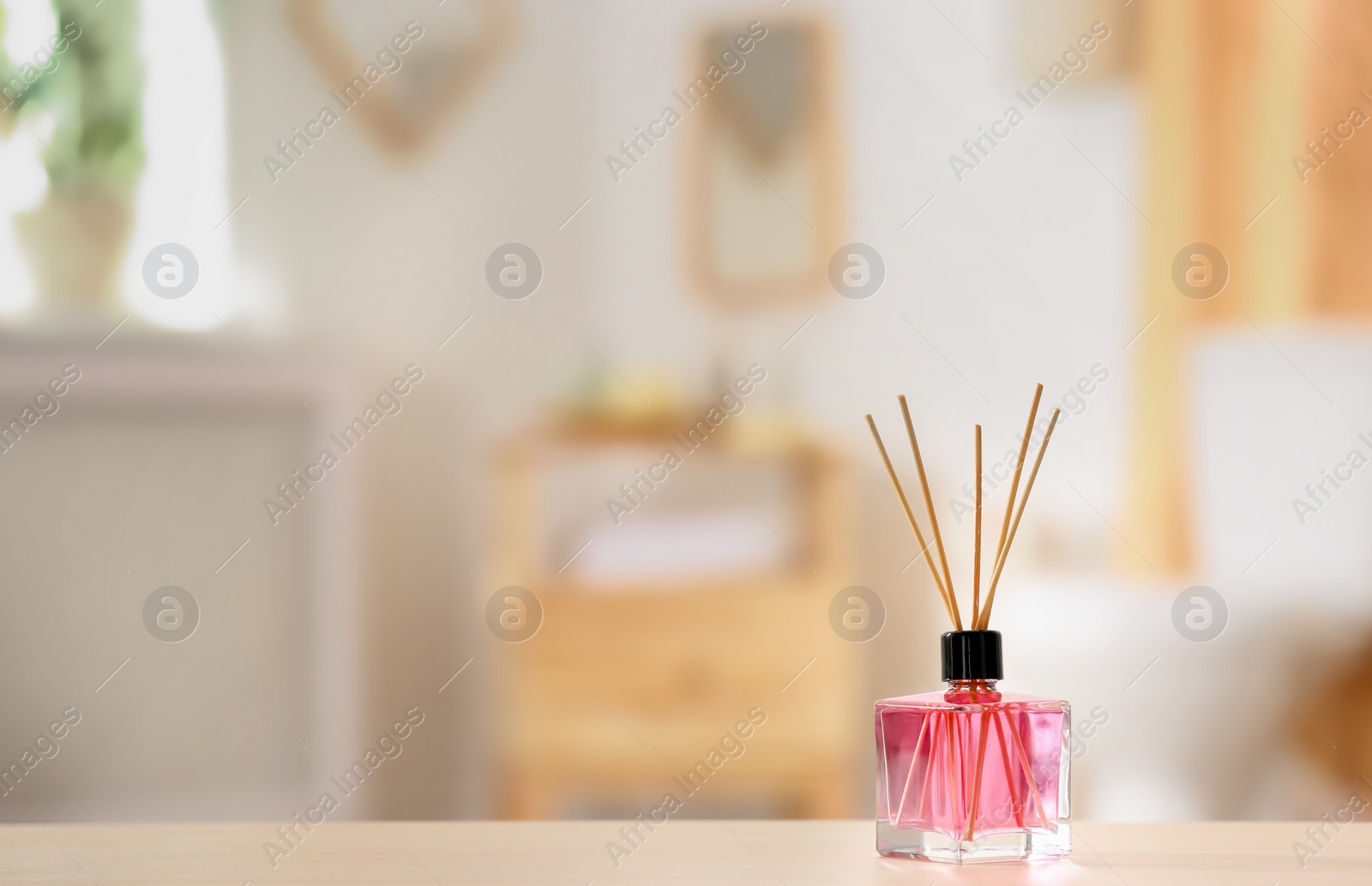 Photo of Aromatic reed air freshener on table against blurred background