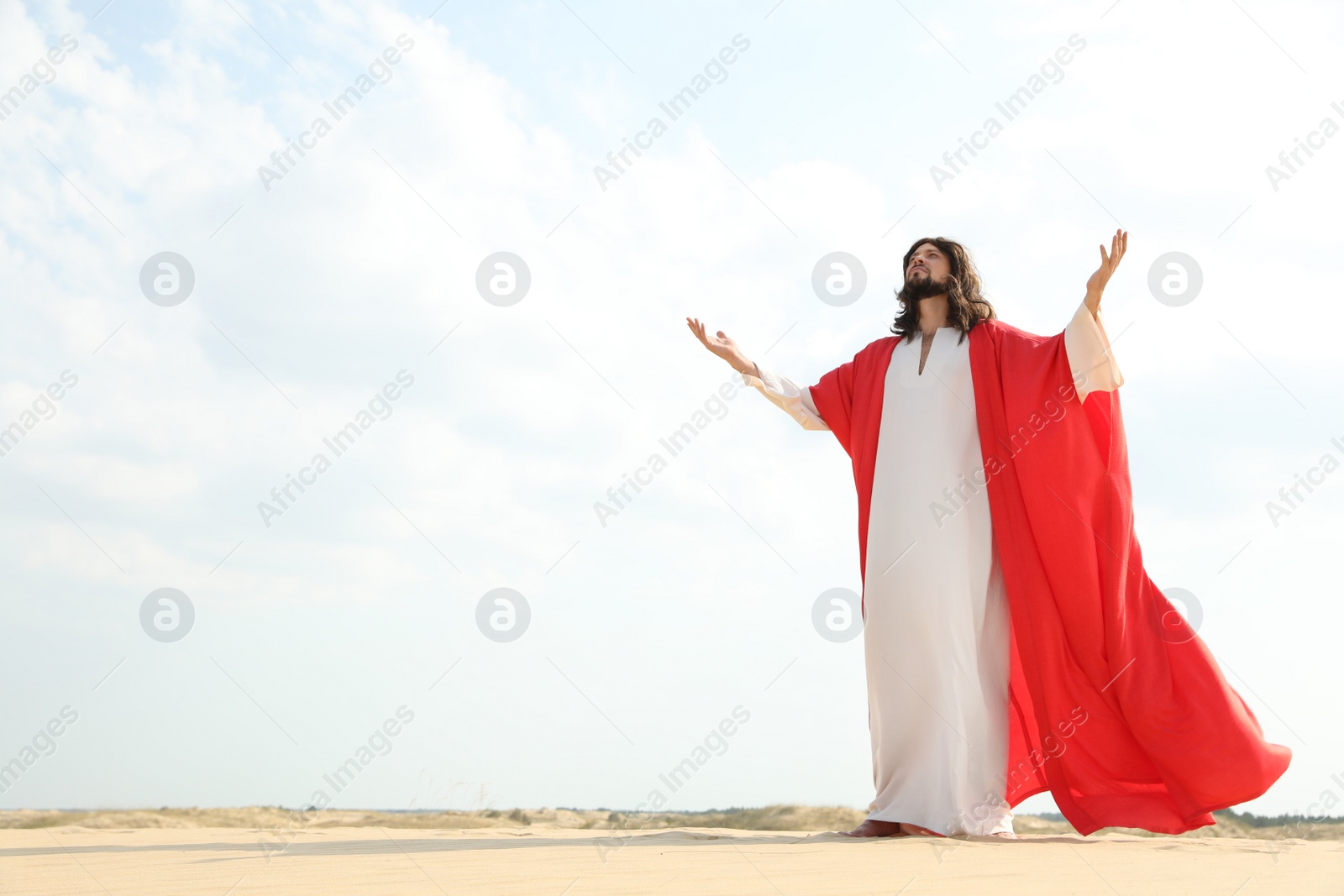 Photo of Jesus Christ raising hands in desert. Space for text