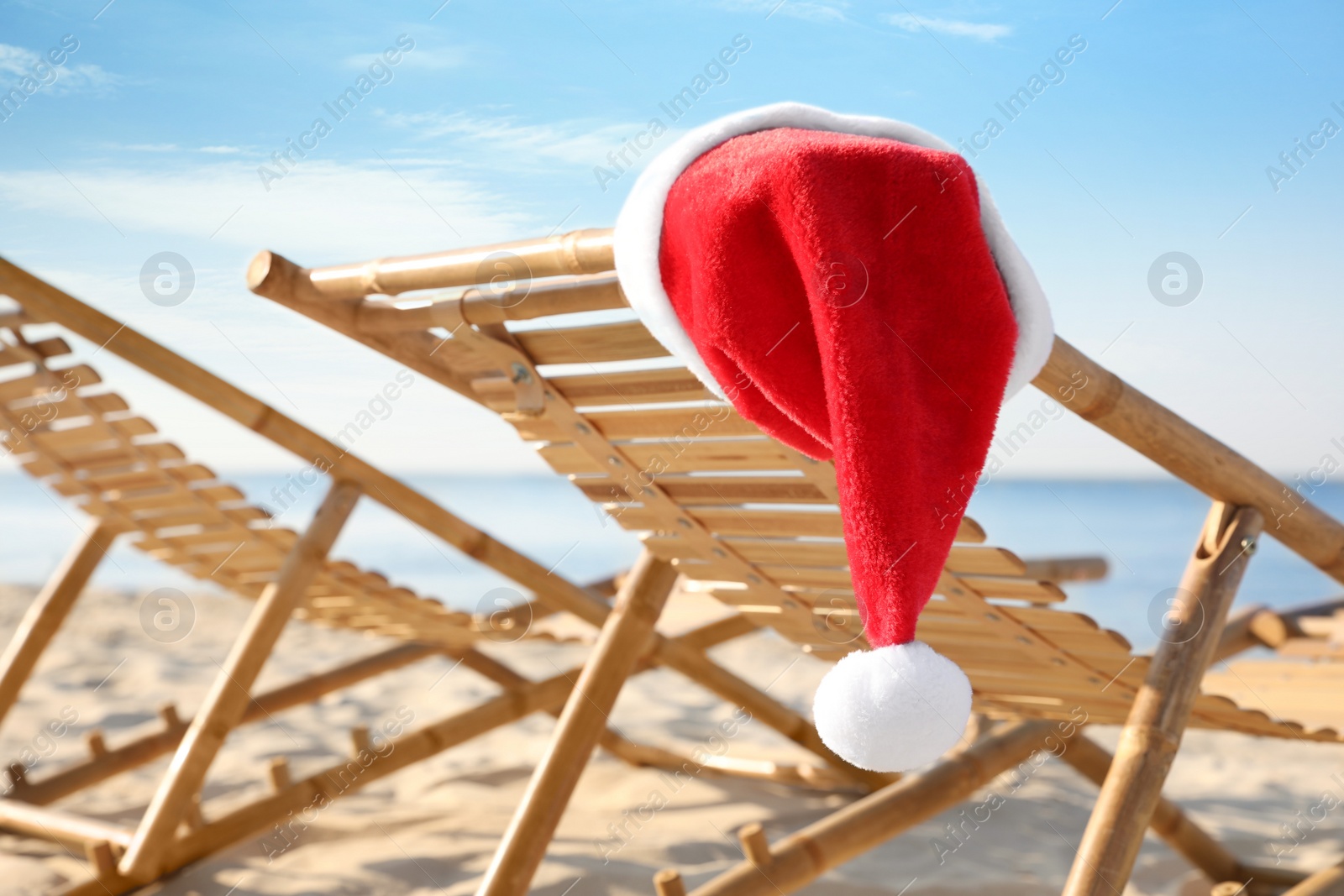 Photo of Sun lounger with Santa's hat on beach, closeup. Christmas vacation