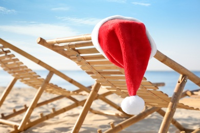 Sun lounger with Santa's hat on beach, closeup. Christmas vacation