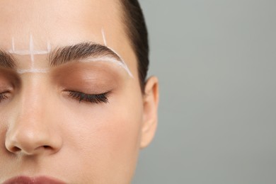 Photo of Eyebrow correction. Young woman with markings on face against grey background, closeup. Space for text
