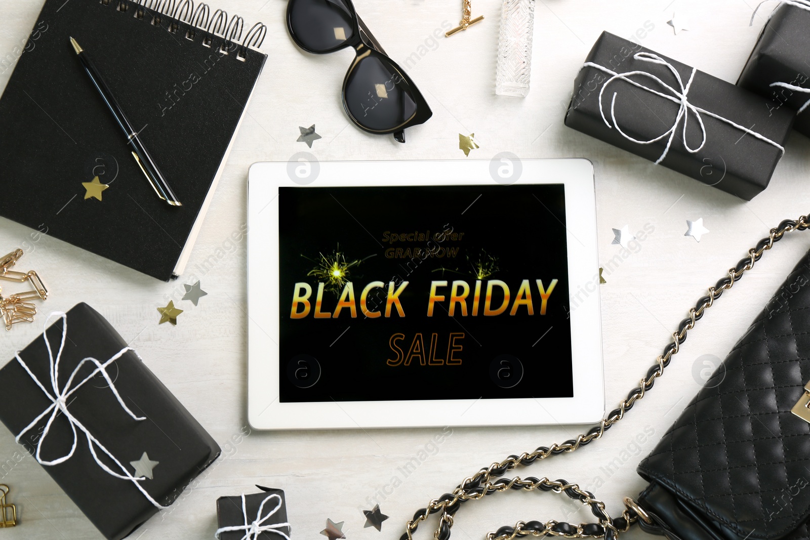 Photo of Flat lay composition with tablet, gifts and accessories on white table. Black Friday sale