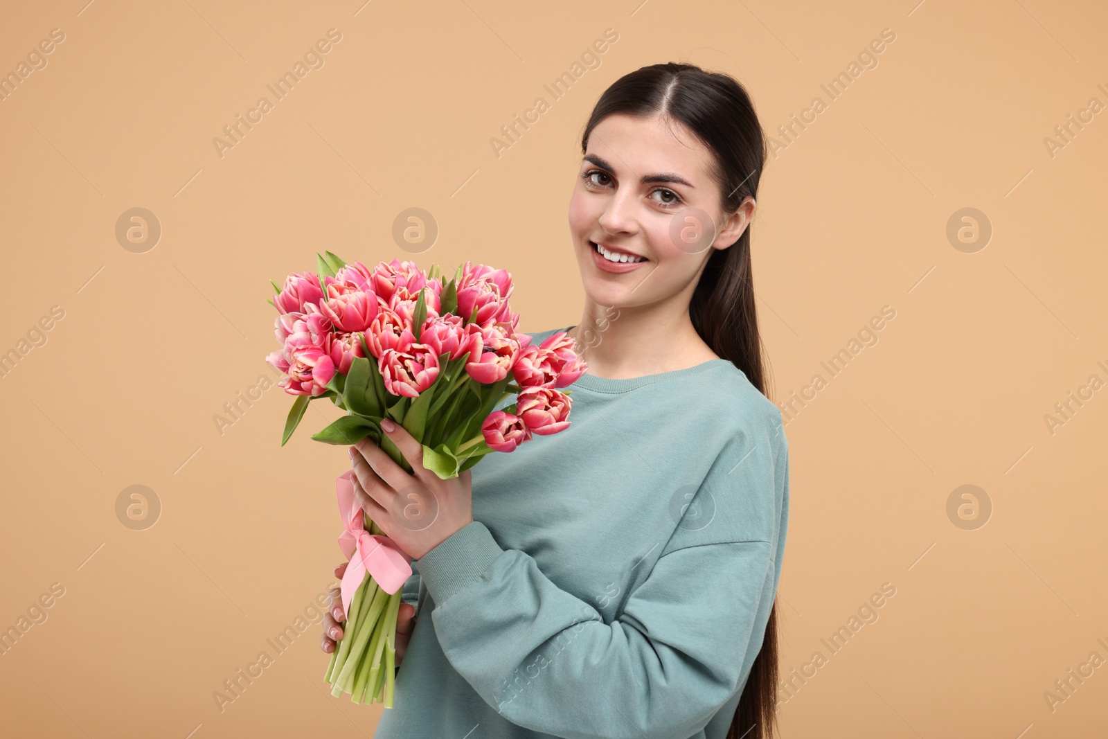 Photo of Happy young woman with beautiful bouquet on beige background