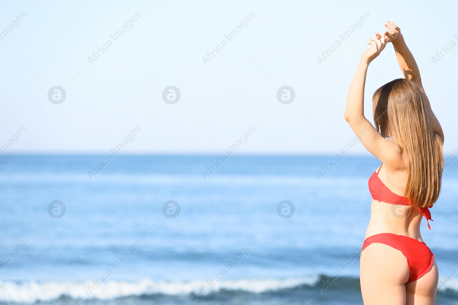 Photo of Young woman in red bikini near sea. Space for text