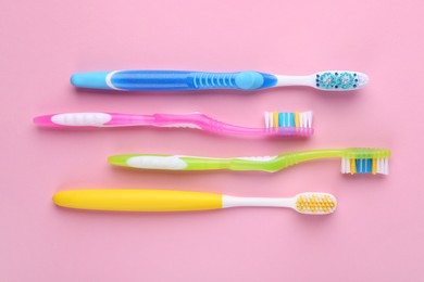 Many different toothbrushes on pink background, flat lay