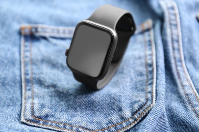 Photo of Modern stylish smart watch on jeans, closeup
