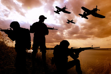 Image of Silhouettes of soldiers with assault rifles and military airplanes patrolling outdoors