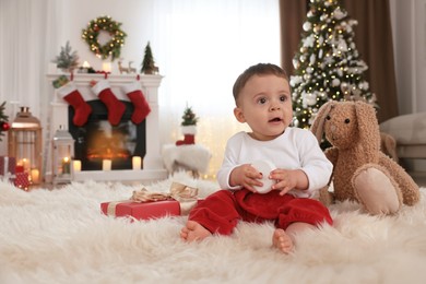 Baby with toys on floor in room decorated for Christmas