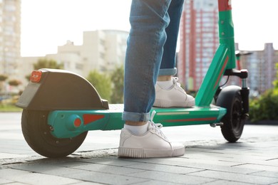 Photo of Woman with modern electric kick scooter on city street, closeup