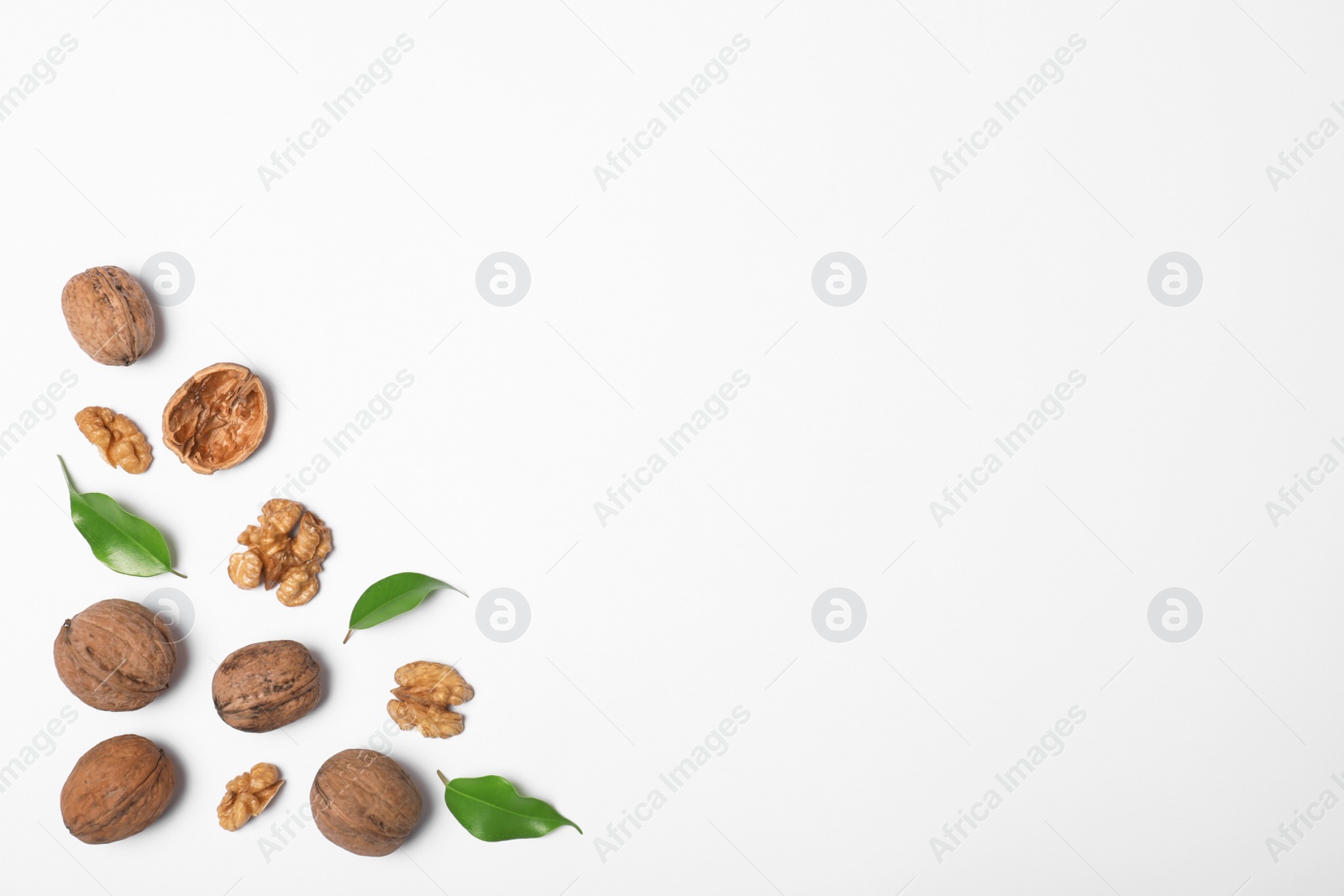 Photo of Walnuts with leaves on white background, flat lay with space for text