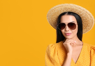 Photo of Beautiful woman wearing sunglasses on yellow background. Space for text