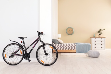 Photo of Bicycle near light wall in stylish room interior