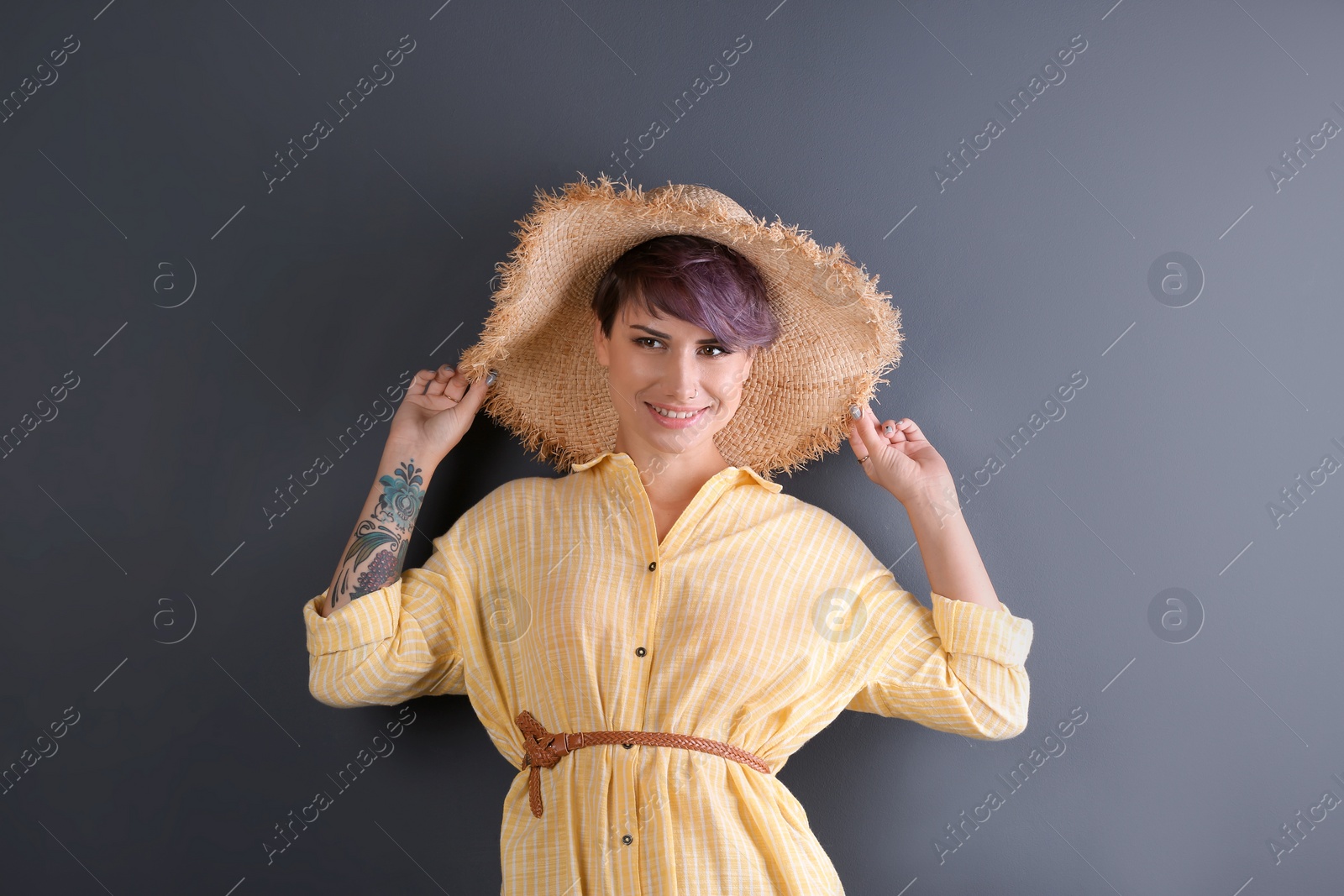 Photo of Trendy young woman with tattoo on color background