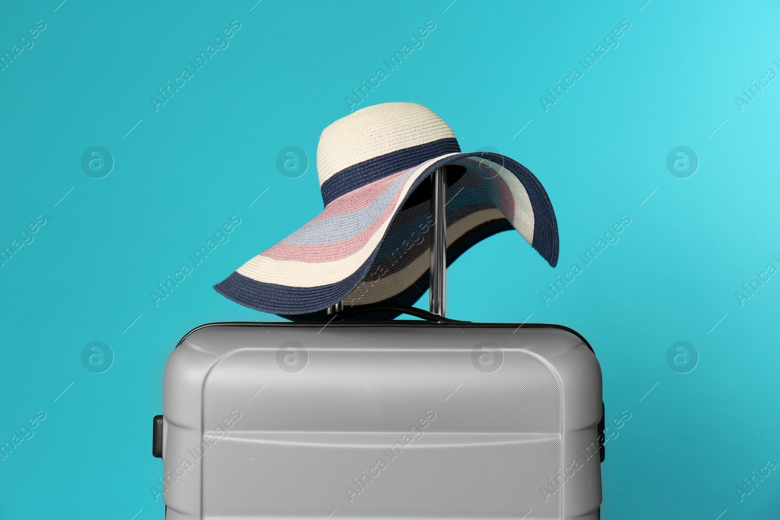 Photo of Stylish suitcase with hat on color background