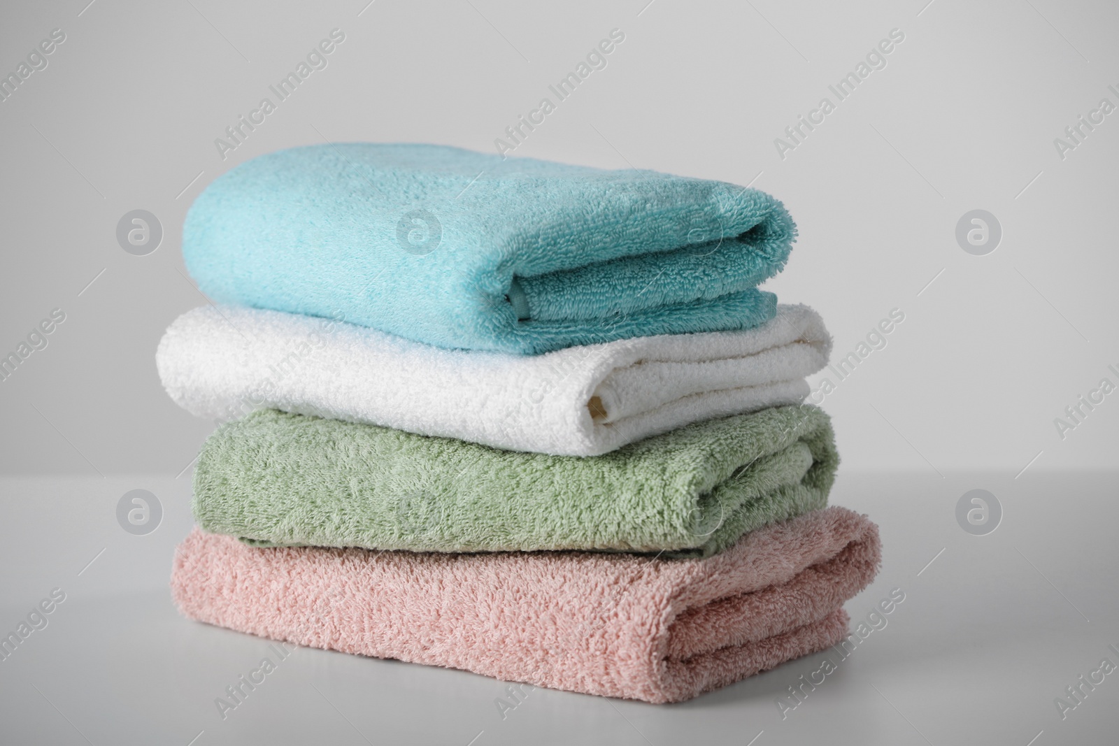 Photo of Stack of folded soft colorful towels on white table