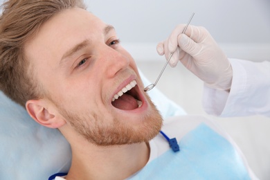 Photo of Dentist examining patient's teeth in modern clinic