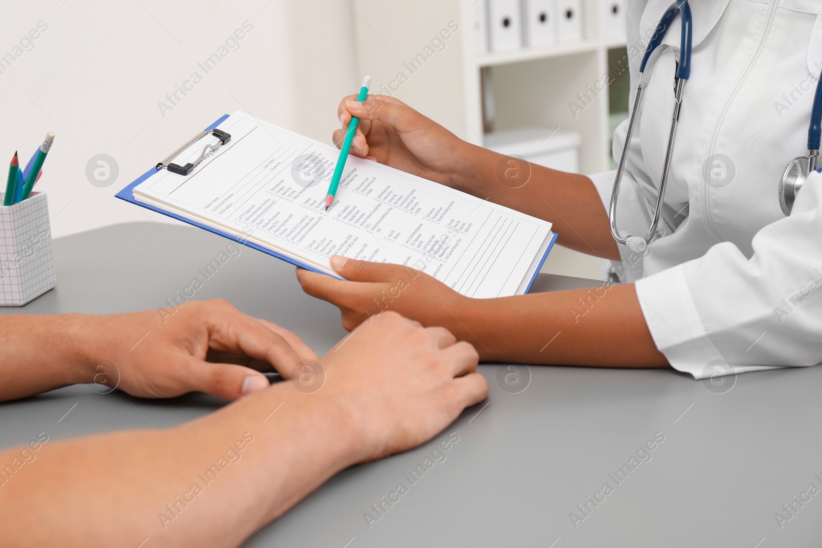 Photo of Female doctor working with patient at table in hospital, closeup