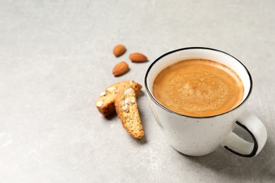 Photo of Tasty cantucci and cup of aromatic coffee on light grey table, space for text. Traditional Italian almond biscuits