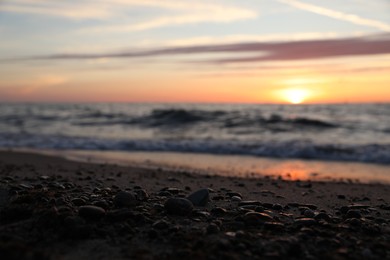 Tropical beach with sand and stones near sea at sunset, selective focus. Space for text