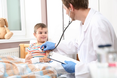 Photo of Doctor examining little child with stethoscope in hospital