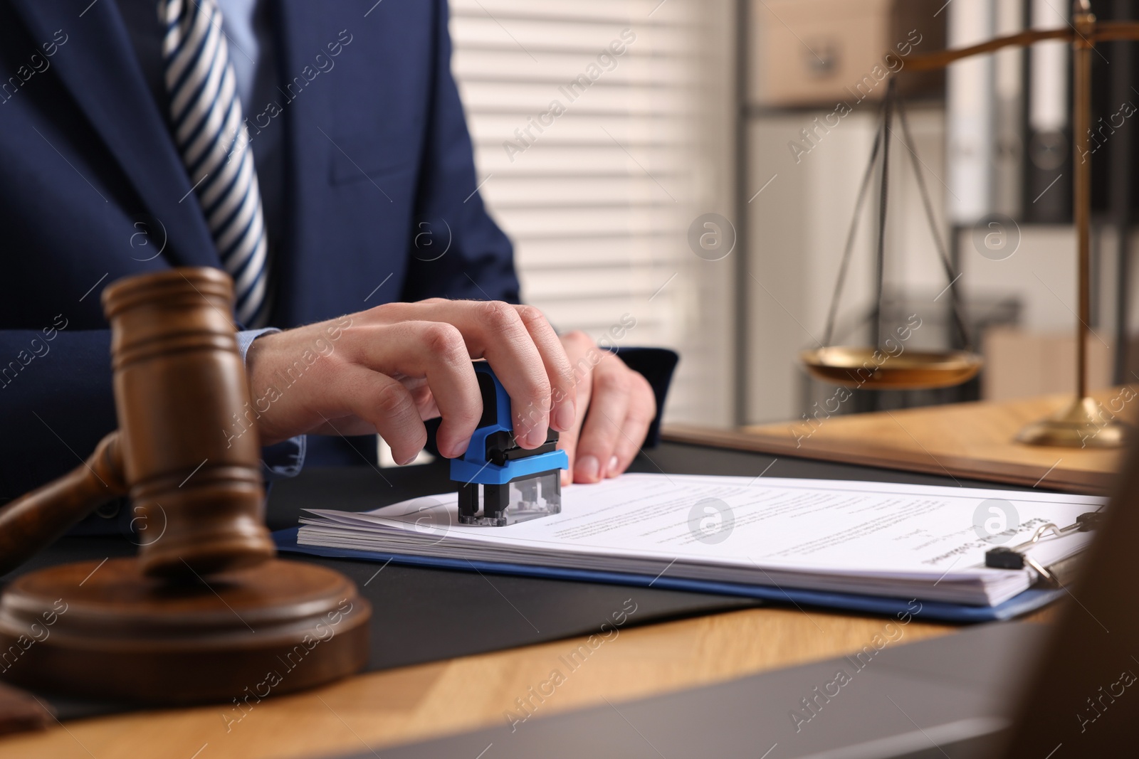 Photo of Notary stamping document at wooden table in office, closeup