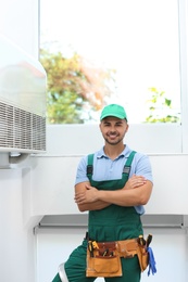 Photo of Professional technician near modern air conditioner indoors