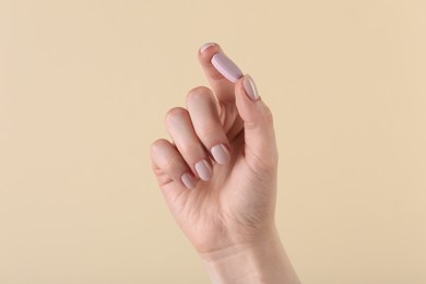 Photo of Woman holding vitamin pill on beige background, closeup. Health supplement