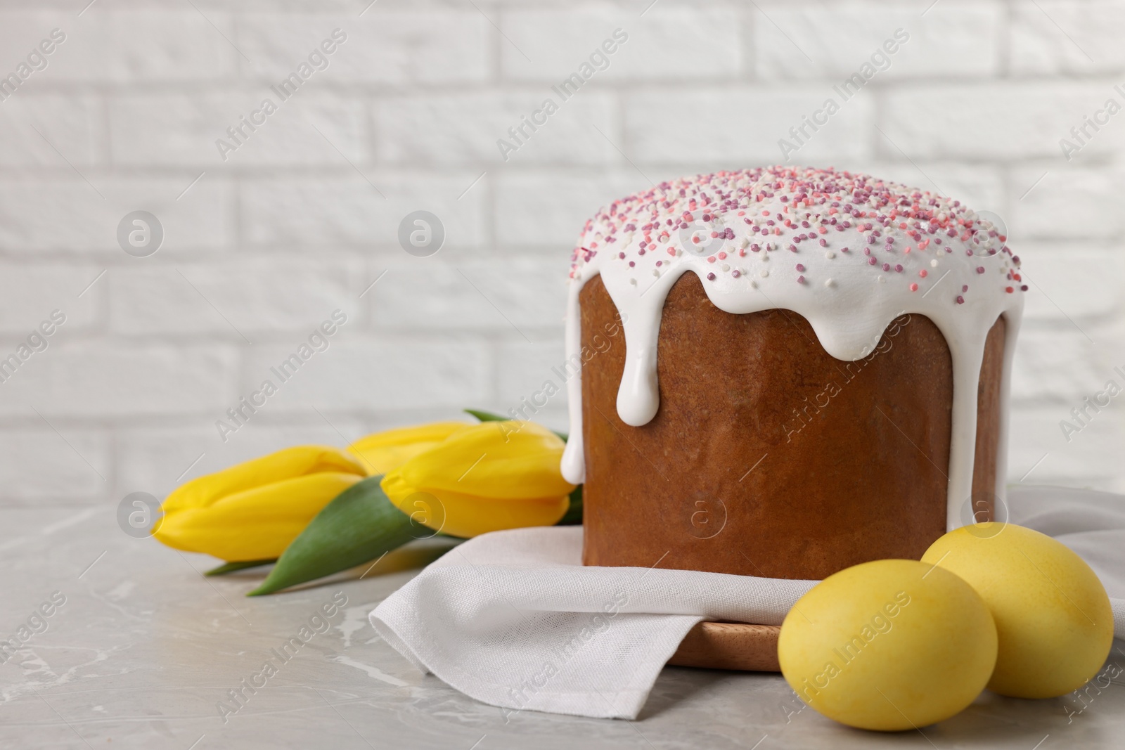 Photo of Tasty Easter cake, decorated eggs and flowers on grey table. Space for text