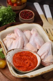 Photo of Fresh marinade and raw chicken on table, closeup