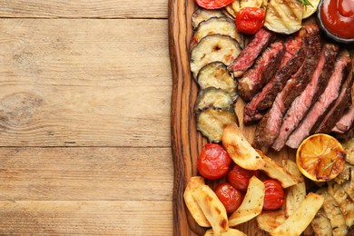Photo of Delicious grilled beef with vegetables, spices and tomato sauce on wooden table, top view. Space for text