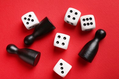 Photo of Many white dices and black game pieces on red background, flat lay