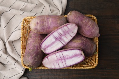 Photo of Purple daikon radishes in wicker basket on wooden table, top view
