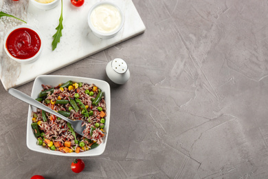 Photo of Tasty brown rice with vegetables served on grey table, flat lay. Space for text