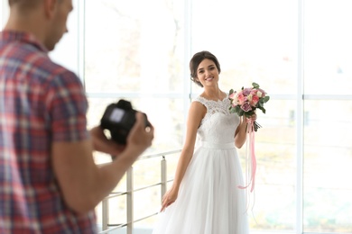 Photo of Professional photographer with camera and beautiful bride in studio