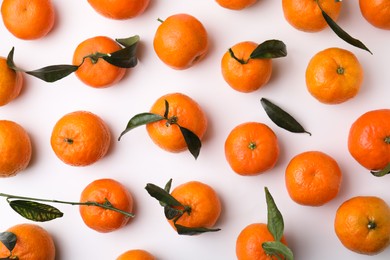 Photo of Fresh ripe tangerines with green leaves on white background, flat lay