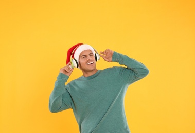 Photo of Happy man with headphones on yellow background. Christmas music