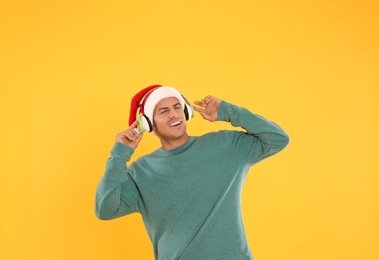 Happy man with headphones on yellow background. Christmas music